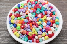 a white bowl filled with lots of colorful beads