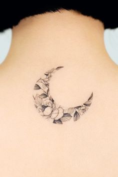 the back of a woman's neck with a crescent tattoo design on her left side