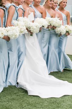 a bride and her bridesmaids are all dressed in blue dresses with white bouquets