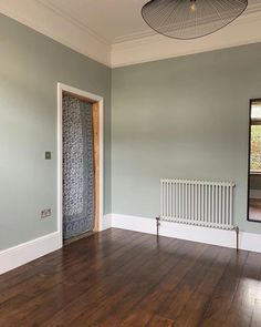 an empty room with hard wood floors and a radiator on the wall, in front of a window