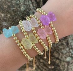 four different colored bracelets on a woman's arm with gold beads and flowers