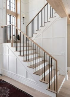 a stair post and railing with an arrow pointing to the top right handrail, in front of a white painted wall