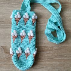 an ice cream crochet cell phone case on a wooden table with a lanyard