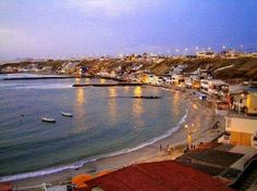 the beach is lined with houses and small boats in the water at dusk, as seen from above