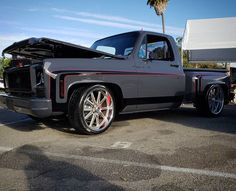 a silver truck parked in a parking lot next to a palm tree