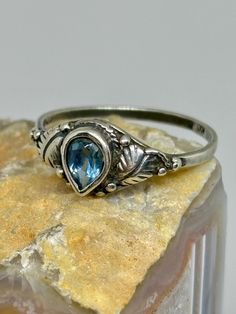 This stunning vintage ring features a beautiful teardrop-shaped blue topaz set in sterling silver. The ring is stamped with "KC 8" and is a perfect size 8. While there is slight wear to the band, as shown in the photos, it does not affect the fit or overall appearance. Add this unique piece to your collection and enjoy its timeless elegance! Ring Teardrop, 8 December, Water Rings, Mens Ring, December Birthstone, Vintage Ring, Solitaire Ring, Sterling Silver Ring, Blue Topaz