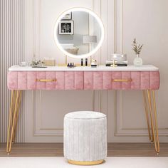 a pink vanity with gold legs and a round mirror on the wall next to it