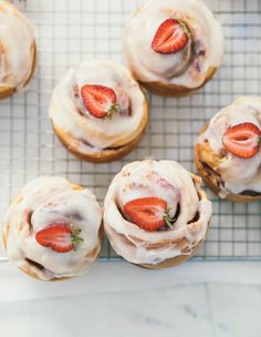 several pastries with strawberries are on a cooling rack, ready to be eaten