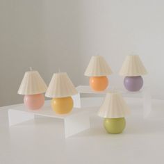 four lamps with different shades on them sitting on top of a white table next to each other