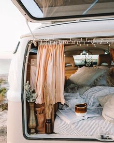 the back of an open van with pillows and blankets in it