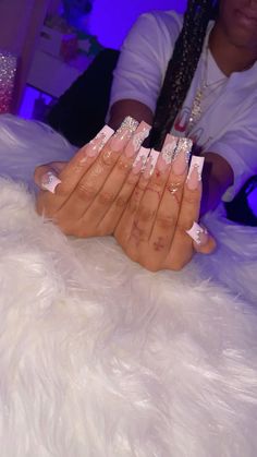 the woman is sitting down with her nails painted pink and silver on her hands, while she