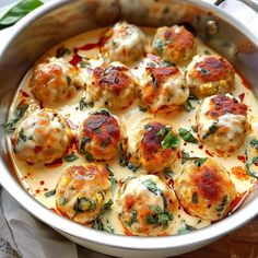 a pan filled with meatballs covered in cheese and sauce on top of a wooden table