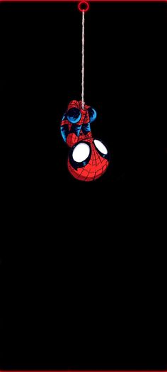 a spider man hanging from a chain in the dark