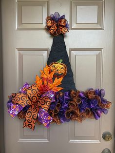 a door decorated with purple and orange ribbons, pumpkins and other decorative items on it