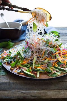 someone is sprinkling shredded vegetables on top of a plate with chopsticks