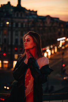 a woman standing in front of a city street at night with her hand on her face