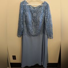 a blue dress hanging up against a wall