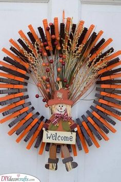 a wreath made out of carrots with a scarecrow on it and a welcome sign hanging from the front door