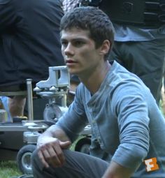 a young man sitting on the ground in front of other people with cameras around him