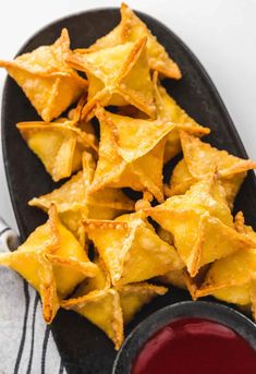 baked tortilla chips with ketchup in a black bowl on a plate