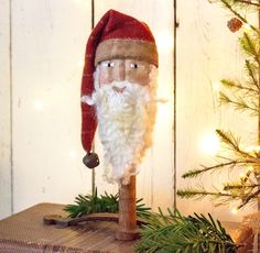 a santa clause doll sitting on top of a wooden box next to a christmas tree