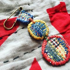 two earrings are sitting on top of a red and white cloth surface, one has a hook in the middle