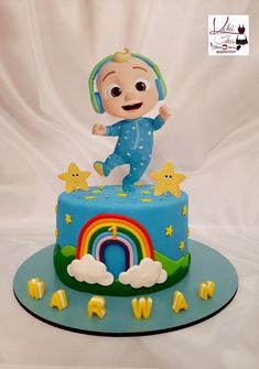 a blue cake with a baby on top and stars around the edges, in front of a white backdrop