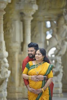 a man and woman standing next to each other in front of an ornate building with columns