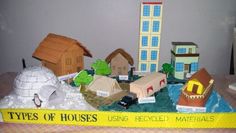 there are many different types of houses on the table together in this picture, and one is made out of cardboard