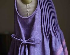 a mannequin is wearing a purple dress with a bow on the front and back