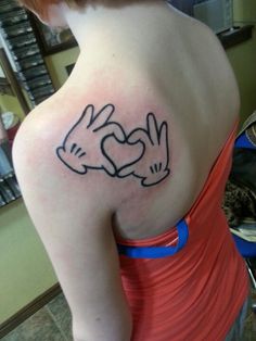 a woman with a tattoo on her shoulder holding hands in the shape of two doves