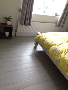 a bed sitting on top of a wooden floor next to a window