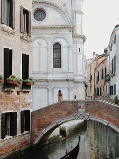 a gondola is floating in the water next to buildings and a bridge with people standing on it