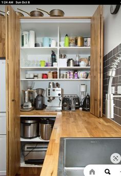 a kitchen with wooden counters and shelves filled with pots, pans and other items