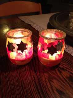 two lit candles sitting on top of a wooden table