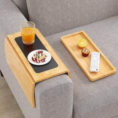 two trays with food and drinks on them sitting on a couch next to a remote control