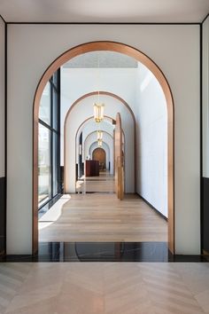 an arched hallway leading to a living room with large windows and wood flooring on both sides