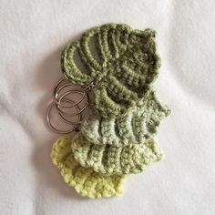 three crocheted keychains are sitting on a white surface, one is green and the other is yellow