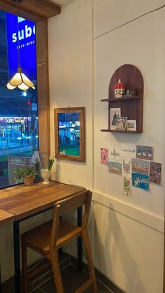 a wooden table sitting in front of a window next to a shelf with pictures on it