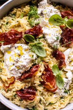 a bowl filled with pasta and meat covered in cheese, herbs and seasoning on top