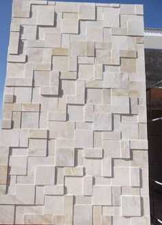 a large white brick wall next to a building under construction with blue sky in the background