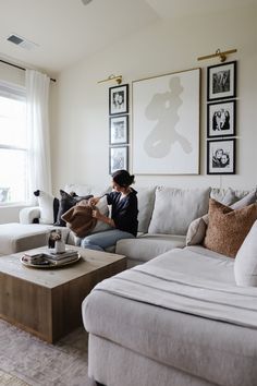 a woman sitting on top of a couch in a living room next to a window