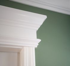 the corner of a room with green walls and white molding on the trimming