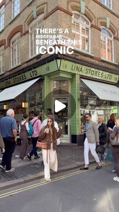 people are walking on the sidewalk in front of a store