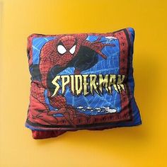 a spiderman pillow sitting on top of a yellow wall