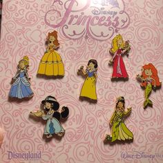 the disney princess pin set is displayed in front of a pink background