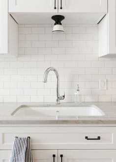 a white kitchen with black and white accessories on the countertop, sink and cabinets