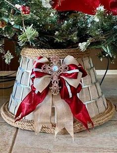 a christmas tree in a basket with red ribbon on the bottom and white bows tied around it