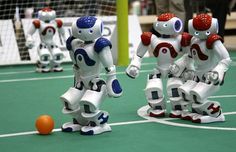 three robot figurines are playing with an orange ball