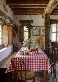 a dining room table covered with a checkered red and white tablecloth next to a window